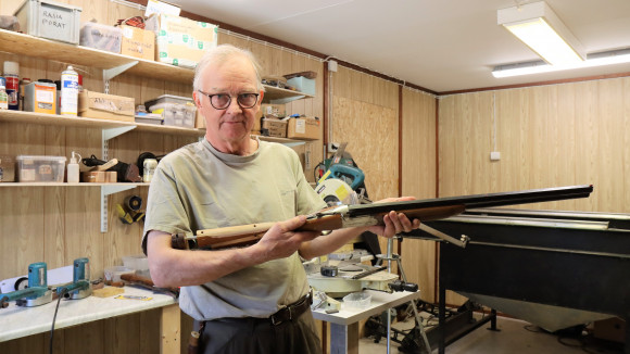 Tukkimestari Markku Tervonen näyttää mittatukilla varustetulla aseella, kuinka kyynärtaitemitalla voi selvittää, onko aseen tukki oikean mittainen