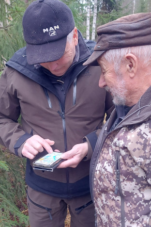 Tuomarit tarkkailevat koiraa maastossa.