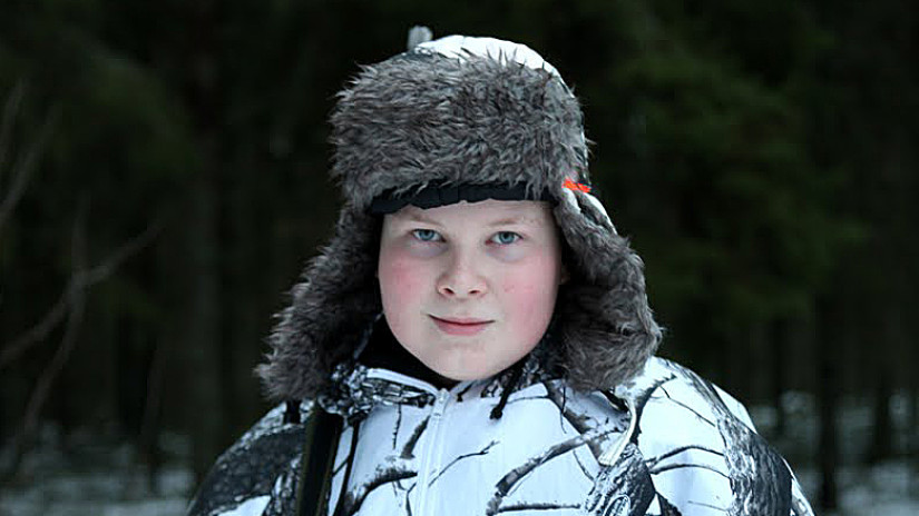 Nuori metsästäjä lumipuvussa.