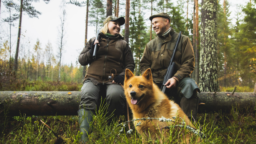 Två jägare och en finsk spets tar en paus i skogen.