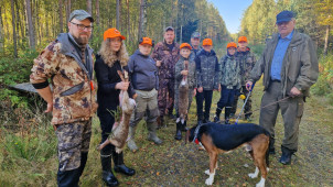 Jänismetsällä ollut porukka seisoo saaliin kanssa metsätiellä.