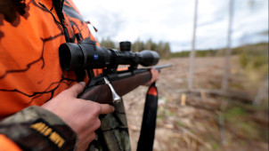 En jägare håller i ett gevär.